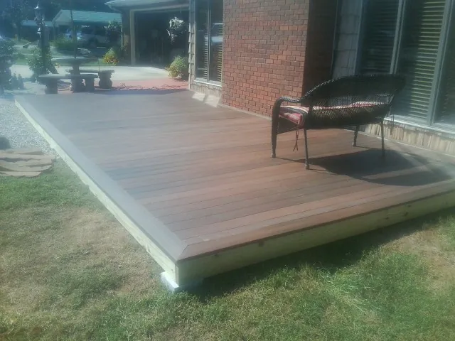 New wood deck and wicker chair beside a brick house in Elk Mound