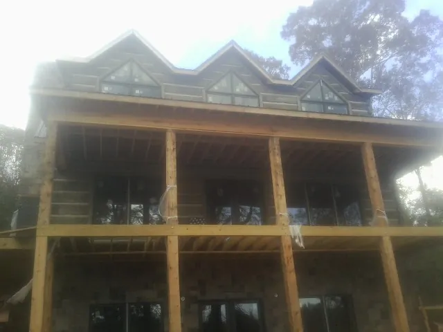 Dormers and porch framing on a large log home under construction — Roof Coating work by our crew in Elk Mound