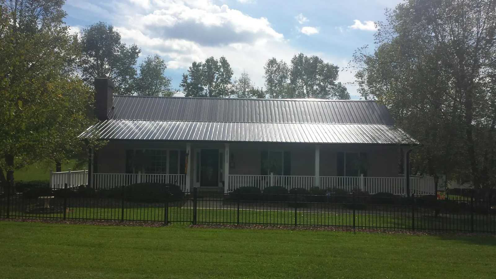 Gray metal roof on a brick ranch with a full width front porch — Gutter Guard Installation work by our crew in Elk Mound