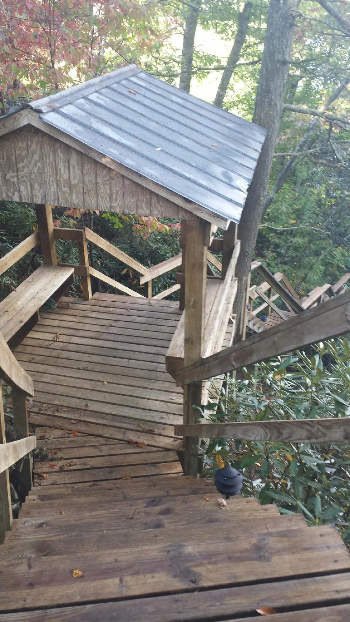 Metal roofed shelter over wooden steps on a wooded walkway — Skylight Repair & Installation work by our crew in Elk Mound