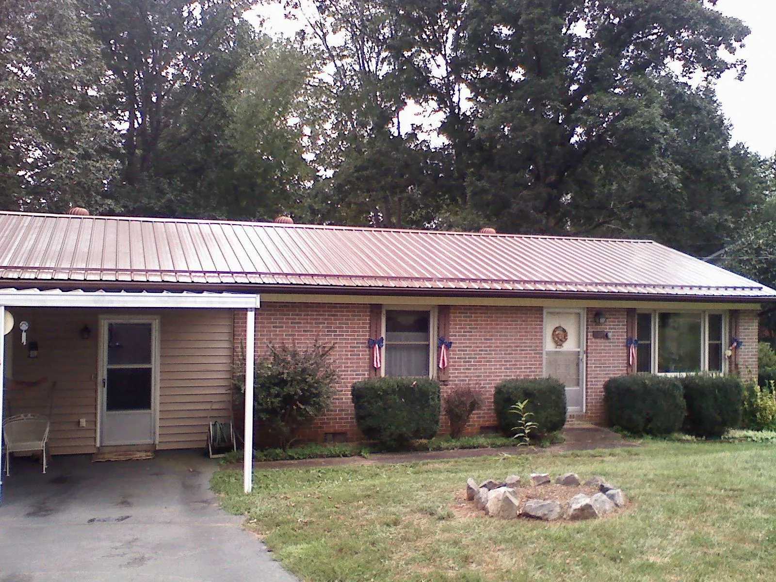 Bronze metal roof and carport on a brick ranch home — Roof Repair work by our crew in Elk Mound