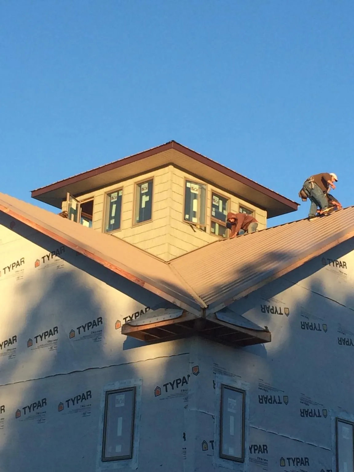 Roofers working around a rooftop cupola on a new metal roof at sunset — Roof Waterproofing in Elk Mound by Roofing Brothers